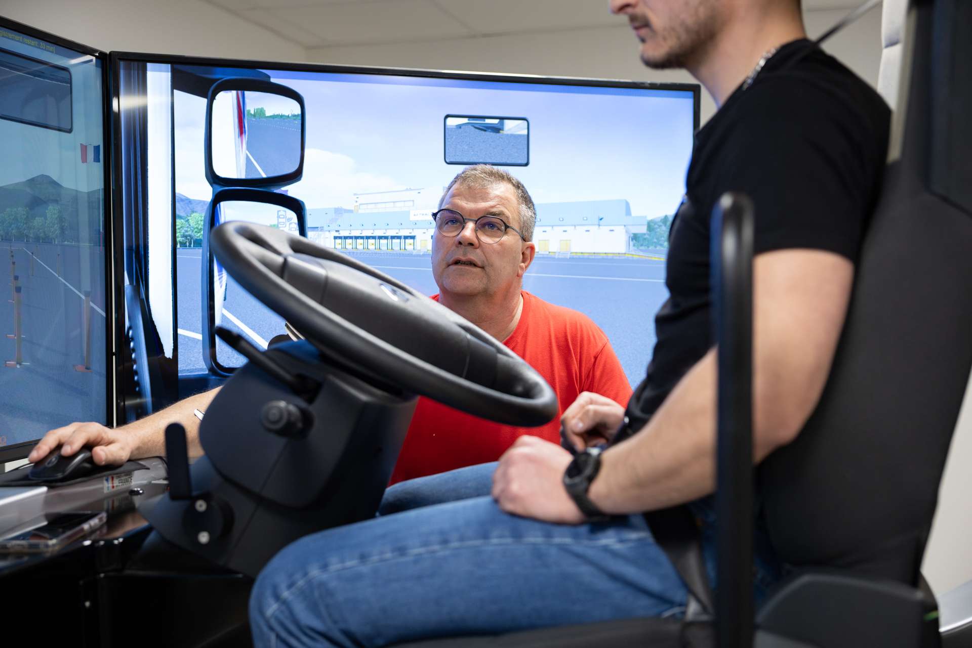 Photo par Antoine Ravet montrant un formateur de conduite de poids lours devant un simulateur de conduite.