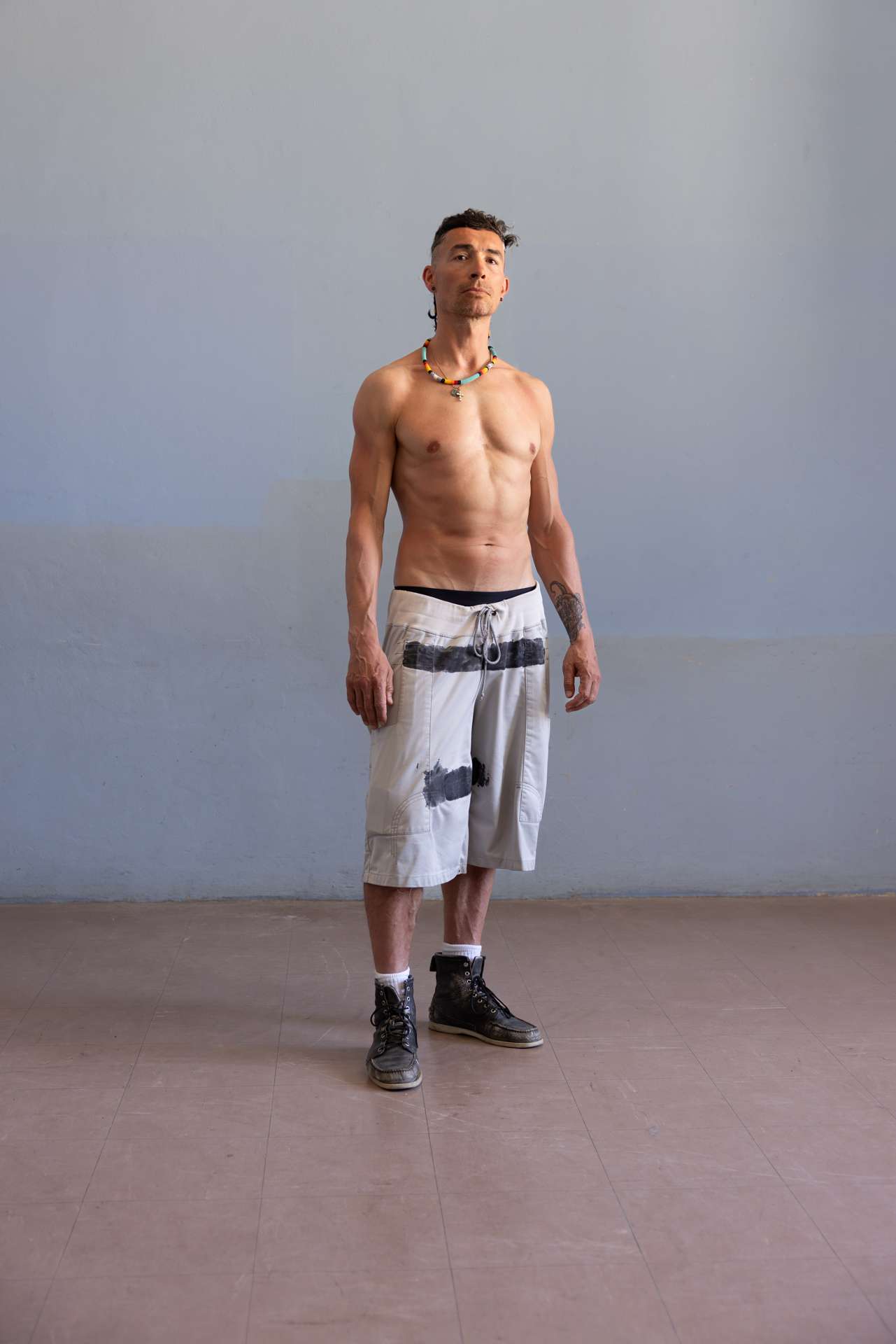 Portrait d'un homme torse nu, qui semble défier l'objectif.