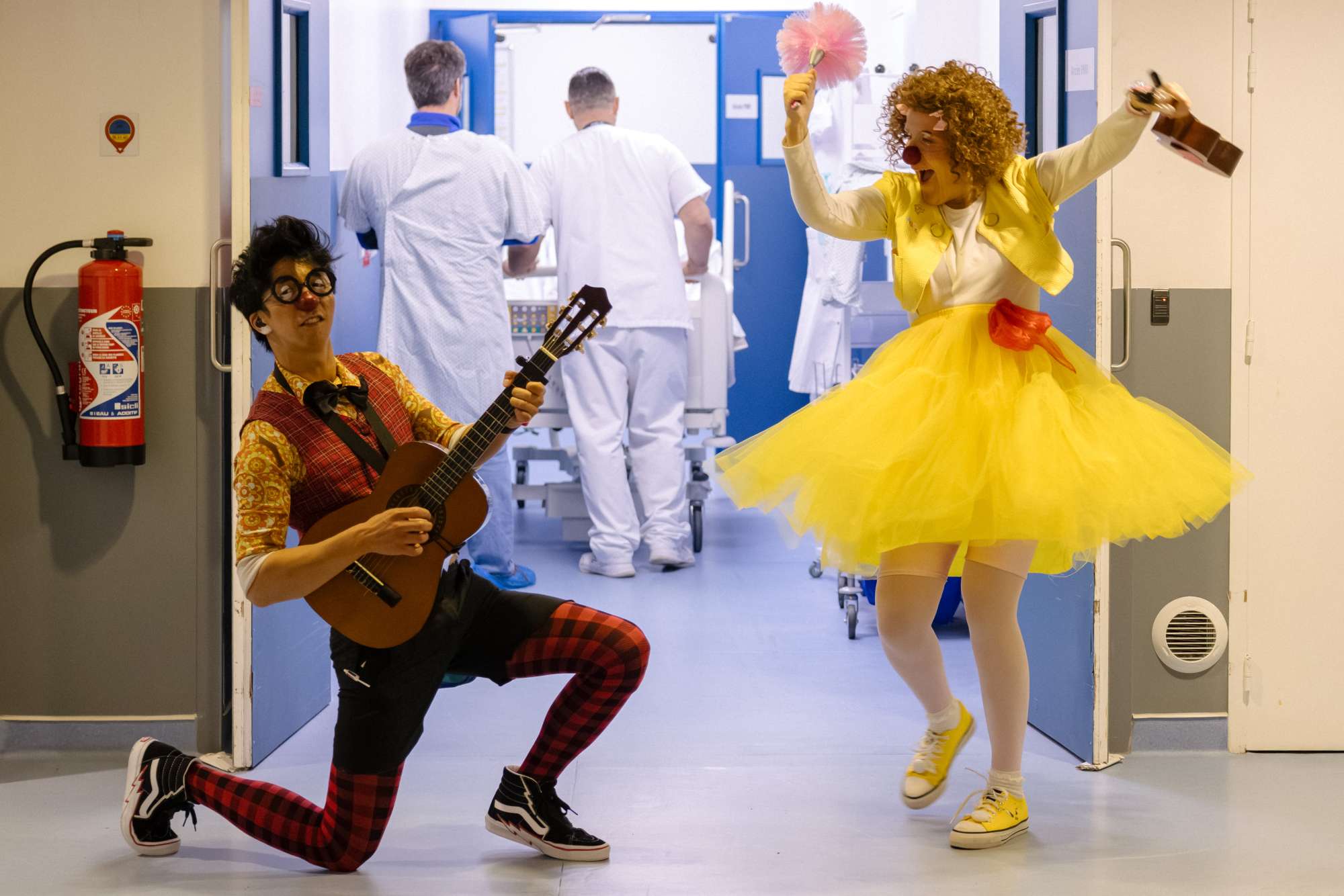 Clowns faisant le spectacle dans un couloir d'hôpital menant au bloc opératoire.