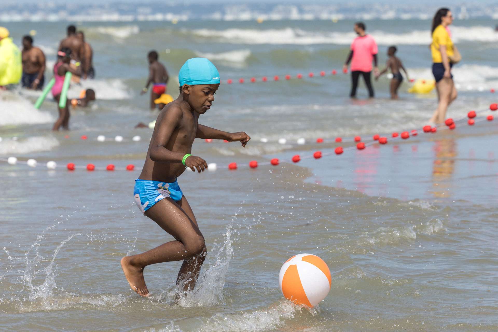 Enfant courant après un ballon sur la plage